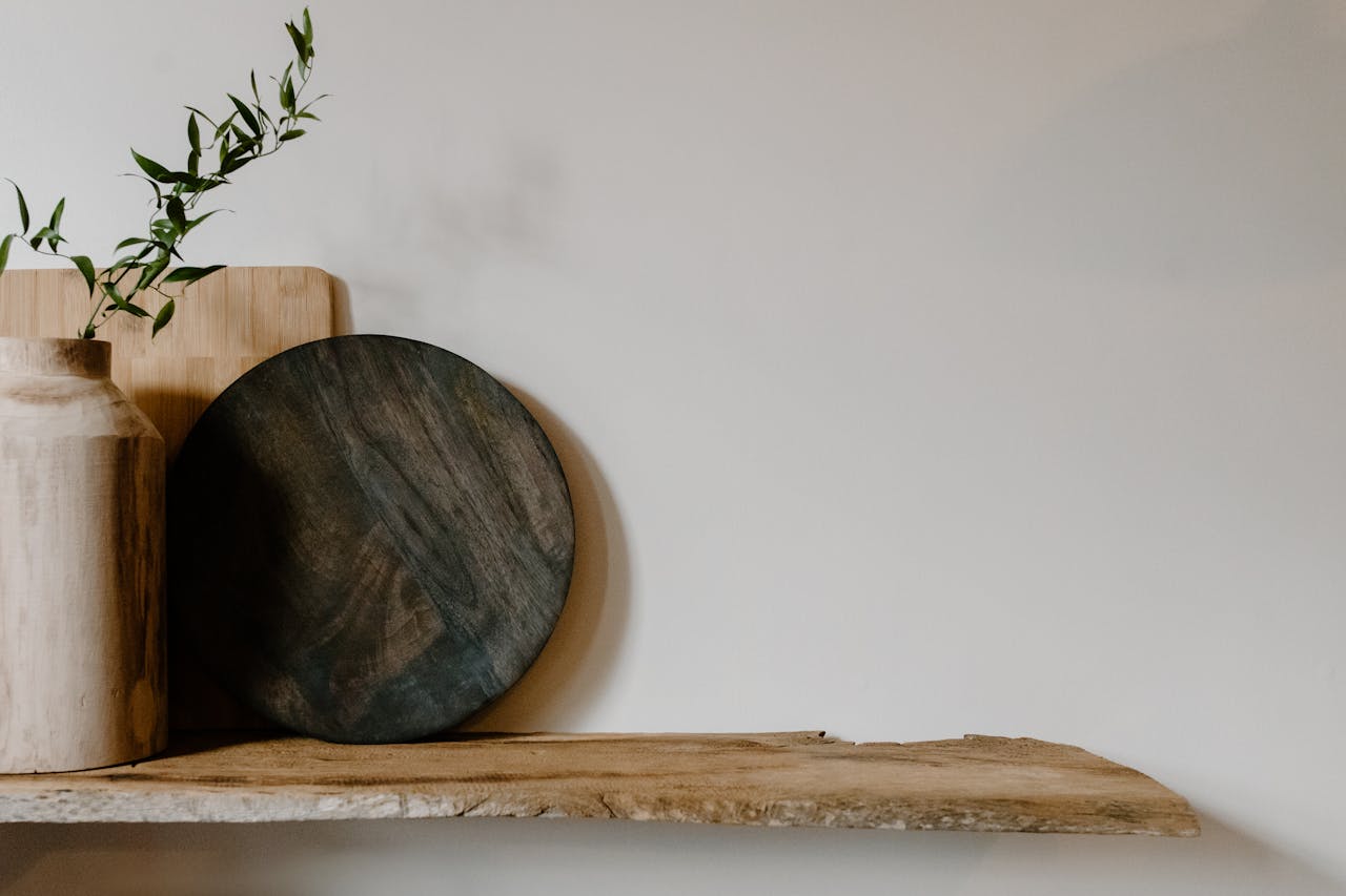 Elegant minimalist arrangement of wooden decor pieces and vase on a wooden shelf.